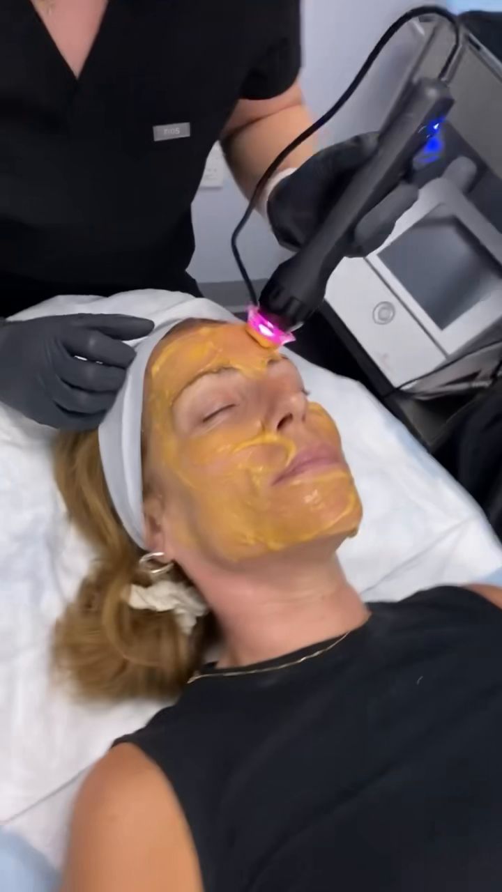 A Hudson Aesthetics MD clinician guiding a Glo2Facial handpiece over a patient’s treatment mask