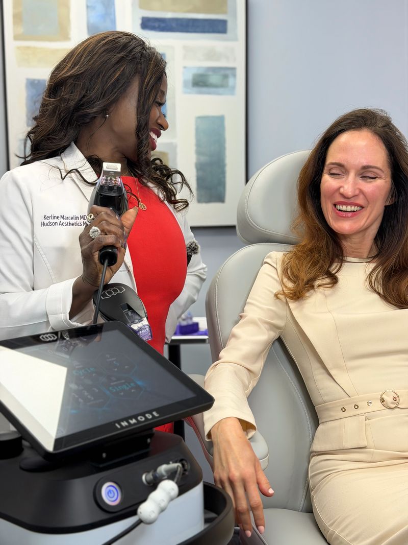 A patient laughing with Dr. Kerline Marcelin, who holds the Morpheus8 handpiece, in a Hudson Aesthetics MD treatment room