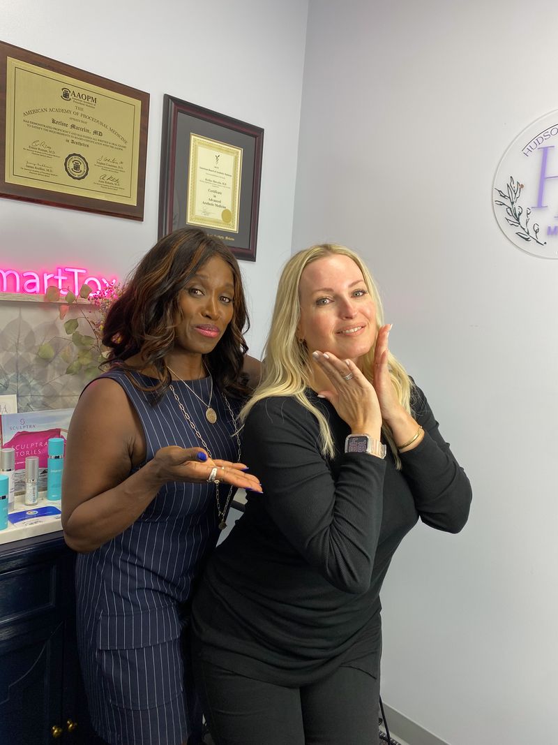 Dr. Kerline Marcelin with a smiling patient in the treatment room at Hudson Aesthetics MD